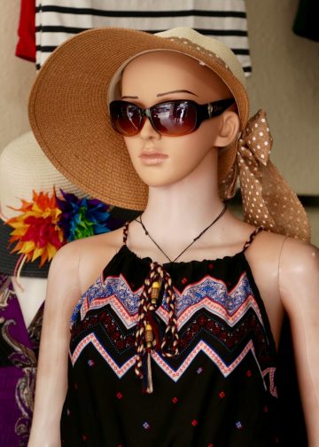 woman in black and red sleeveless dress wearing brown sun hat and sunglasses