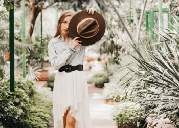 a person in a white dress and black boots holding a hat
