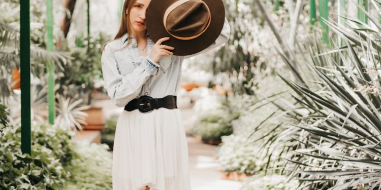 a person in a white dress and black boots holding a hat