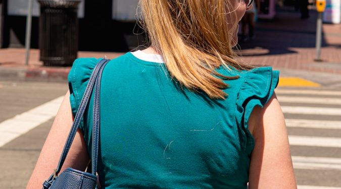 Woman walking on a crosswalk near a building.