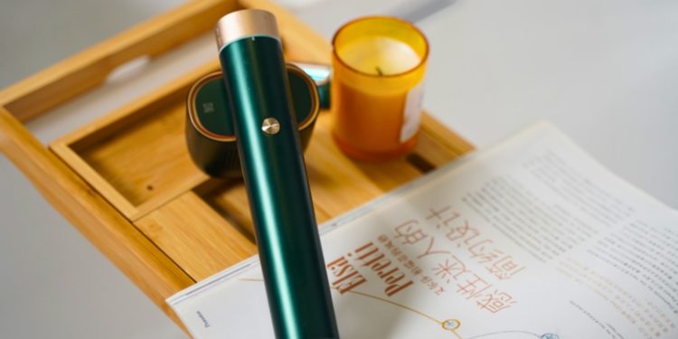 A pen sitting on top of a desk next to a candle