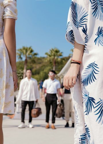 a group of people walking down a sidewalk next to a body of water